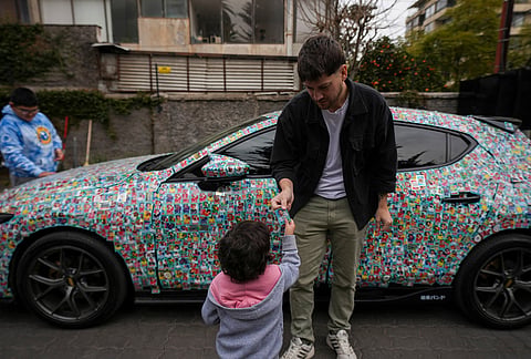 Chilean social media influencer Ariel Osses gives a Lionel Messi Panini sticker to a child as he visits a home for pediatric cancer patients to let the children help him cover his car with soccer stickers in Santiago, Chile.
