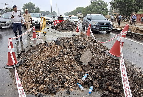 Police personnel inspect and secure the caved-in section of the Jaipur-bound carriageway on the Delhi-Gurugram Expressway (NH-48) near Narsinghpur following heavy rainfall, in Gurugram, Wednesday, July 8, 2026. 