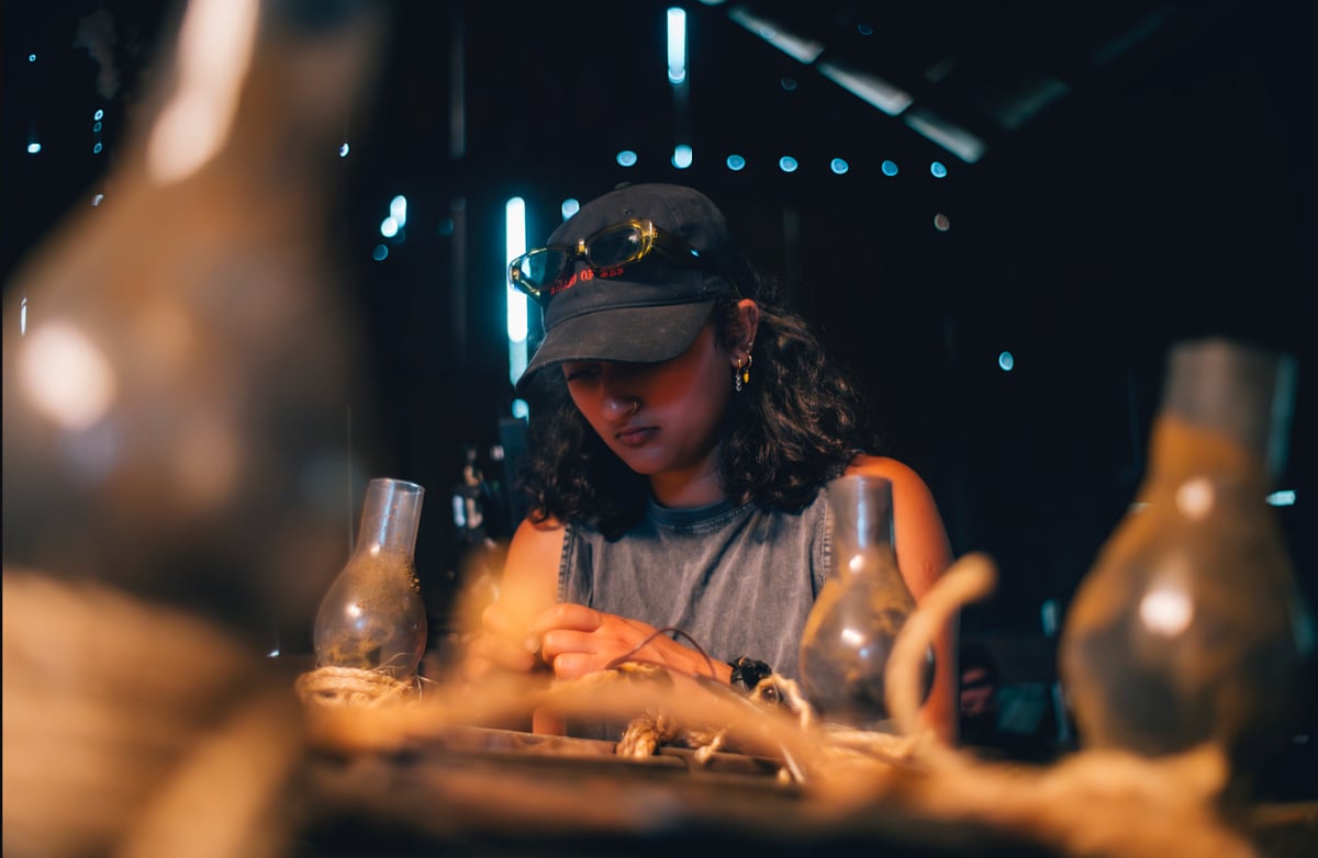 A person wearing a cap carefully works in a dimly lit space
