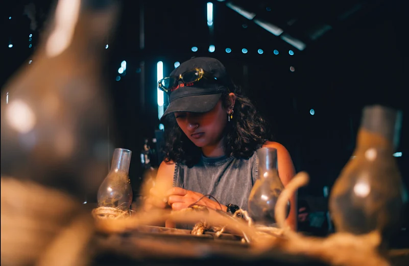 A person wearing a cap carefully works in a dimly lit space