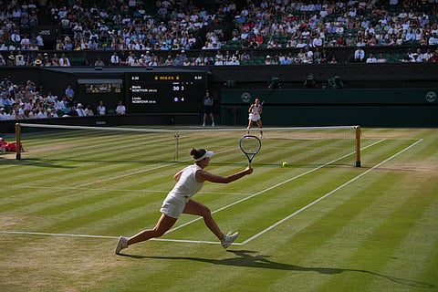 Linda Noskova of the Czech Republic returns the ball to Marta Kostyuk of Ukraine, background, in their semifinal women's singles match at the Wimbledon Tennis Championships in London.