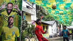 Young boys play football in a street decorated with Brazilian flags and a large poster of footballer Neymar Jr ahead of FIFA World Cup 2026, in Thiruvananthapuram. - Photo: PTI
