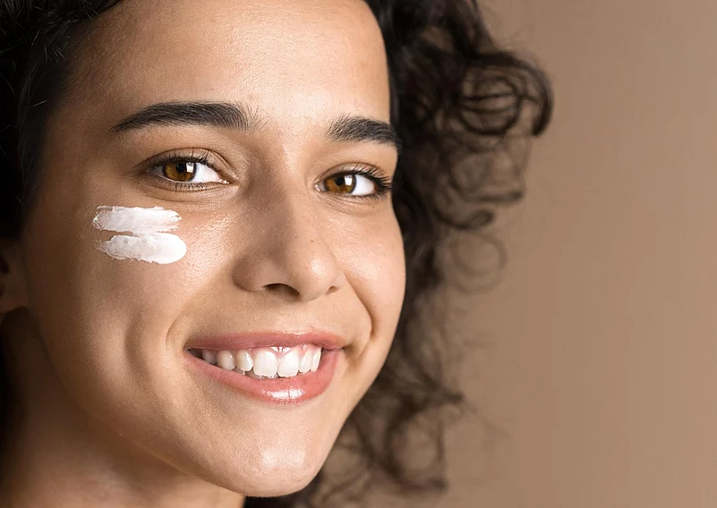 Smiling woman with face cream on her cheek