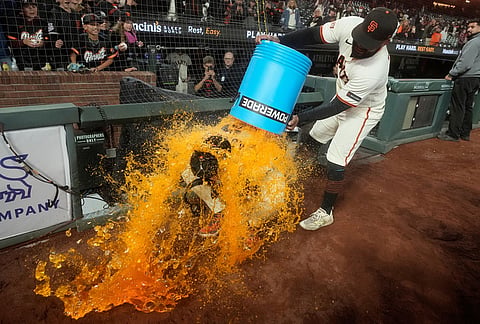San Francisco Giants' Willy Adames, bottom, is doused by Heliot Ramos after a baseball game against the Colorado Rockies in San Francisco. 