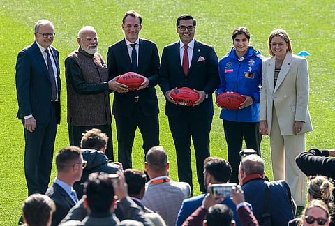 Prime Minister Narendra Modi poses with his Australian counterpart Anthony Albanese and others while holding personalised Australian Football League footballs during a visit to the Melbourne Cricket Ground, in Melbourne, Australia. 