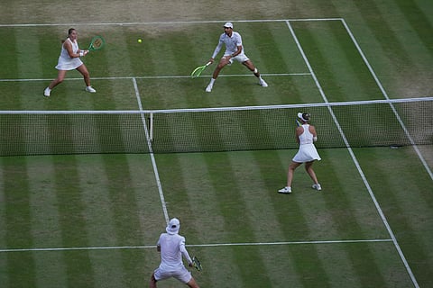 Jelena Ostapenko of Latvia, top left and playing partner Marcelo Arevalo of El Salvador, play a return to Marc Polmans of Australia and Storm Hunter of Australia during their mixed doubles final match at the Wimbledon Tennis Championships in London.