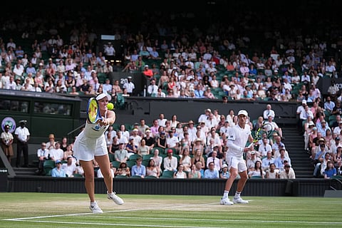 Storm Hunter of Australia plays a backhand next to her playing partner Marc Polmans of Australia during their mixed doubles final match against Jelena Ostapenko of Latvia and Marcelo Arevalo of El Salvador, at the Wimbledon Tennis Championships in London.