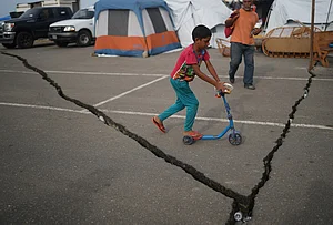 | Photo: AP/Ariana Cubillos : A boy rides a skateboard in a makeshift shelter in a parking lot after earthquake in La Guaira, Venezuela.