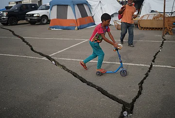 | Photo: AP/Ariana Cubillos : A boy rides a skateboard in a makeshift shelter in a parking lot after earthquake in La Guaira, Venezuela.
