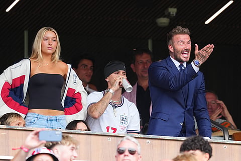 English former soccer player David Beckham gestures from the stands joined by his children, Harper, left, and Romeo ahead of a World Cup quarterfinal soccer match between England and Norway in Miami Gardens, Fla., Saturday, July 11, 2026.