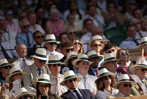 Spectators wearing hats watch the men's singles semifinal match at the Wimbledon Tennis Championships in London, Friday, July 10, 2026.