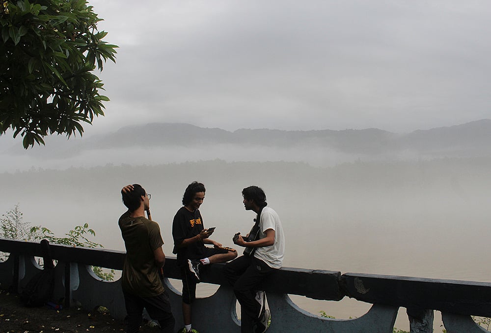 People sit at a platform amid misty morning following rainfall, in Rishikesh, Uttarakhand. - | Photo: PTI