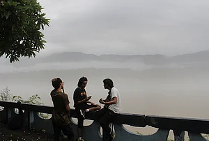 | Photo: PTI : People sit at a platform amid misty morning following rainfall, in Rishikesh, Uttarakhand.