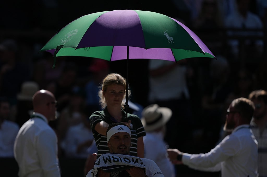 Alexander Zverev of Germany sits under an umbrella during a change over as he plays against Jannik Sinner of Italy during the mens singles final at Wimbledon Tennis Championships in London