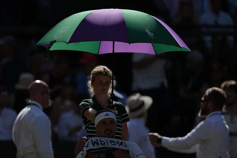 Alexander Zverev of Germany sits under an umbrella during a change over as he plays against Jannik Sinner of Italy during the mens singles final at Wimbledon Tennis Championships in London