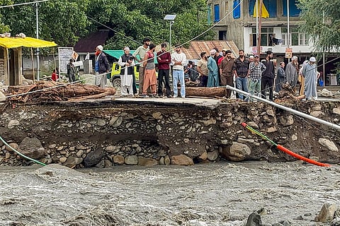 People stand near a damaged road following flash floods triggered by a cloudburst in the Overa area, near Pahalgam, Anantnag district, Jammu and Kashmir.