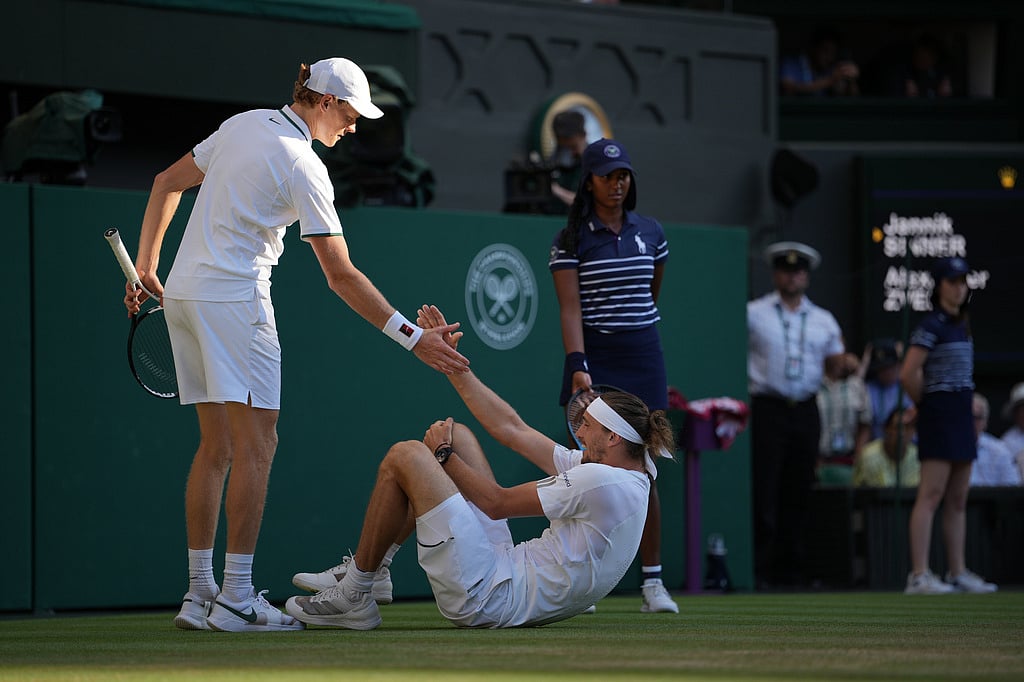 Jannik Sinner of Italy, left helps up Alexander Zverev of Germany who fell during the mens singles final at Wimbledon Tennis Championships in London