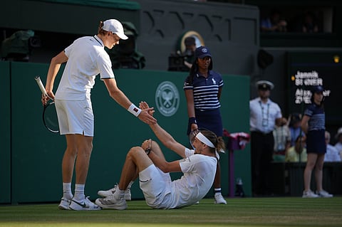 Jannik Sinner of Italy, left helps up Alexander Zverev of Germany who fell during the men's singles final at Wimbledon Tennis Championships in London