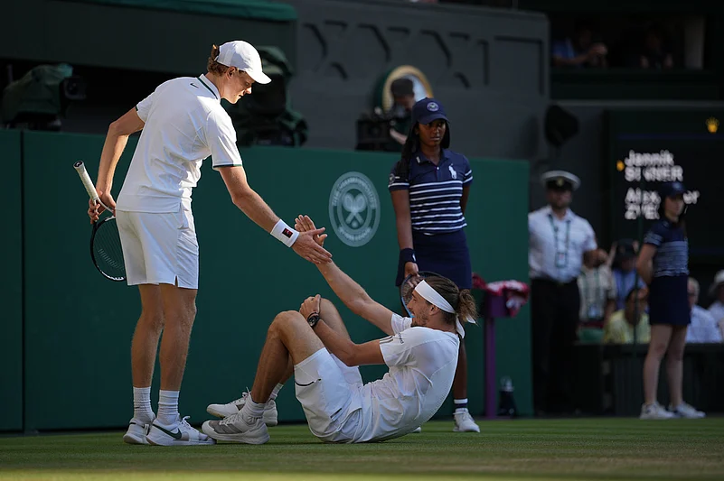 Jannik Sinner of Italy, left helps up Alexander Zverev of Germany who fell during the mens singles final at Wimbledon Tennis Championships in London