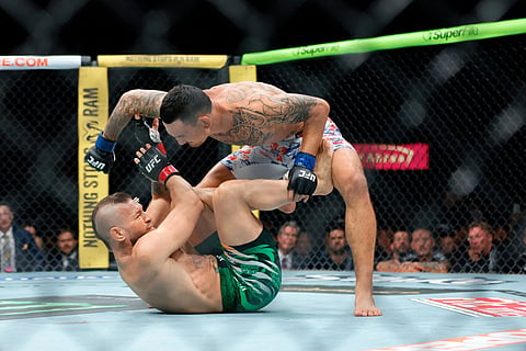 Max Holloway punches Conor McGregor after McGregor falls at the start of a welterweight fight during UFC 329 in Las Vegas.