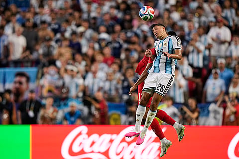 Argentina's Nahuel Molina (26) heads the ball against Switzerland's Dan Ndoye, left, during the World Cup quarterfinal soccer match