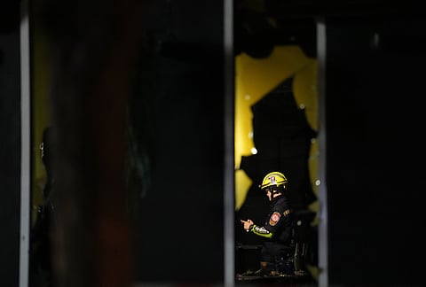 A rescuer is seen inside the site of a fire at a pub in Bangkok, Thailand.
