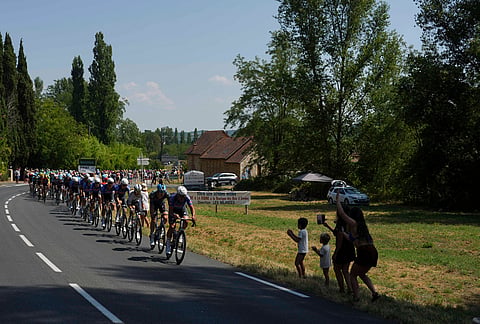 Spectators cheer as the pack rides riders past them during the eighth stage of the Tour de France cycling race with start in Perigueux and finish in Bergerac, France, Saturday, July 11, 2026. 