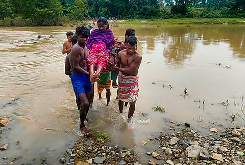 People carry a pregnant woman across a flooded river to reach a hospital, in Savmarangbeda village, Khunti district, Jharkhand.