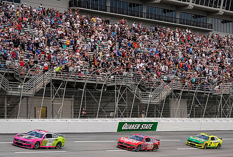 Ryan Blaney, Joey Logano, and Austin Cindric, from left, run during a NASCAR Cup Series auto race in Hampton, Georgia. 