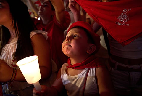 Revelers hold candles and red kerchiefs as they sing "Pobre de Mí," marking the end of nine days of bull runs, music and dancing during the San Fermín festival in Pamplona, northern Spain.