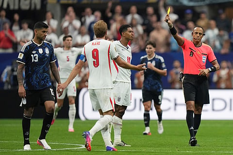 Referee Ismail Elfath shows the yellow card to Argentina's Cristian Romero (13) during the World Cup semifinal soccer match