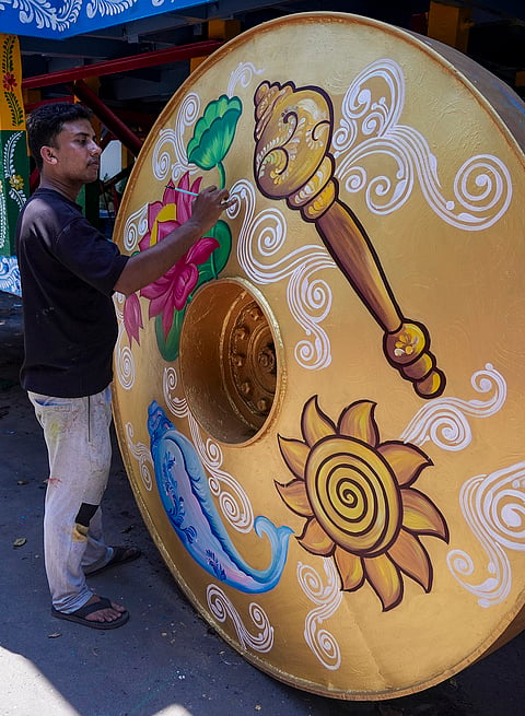 An artist paints a wheel of Lord Jagannath's chariot ahead of the Rath Yatra festival, in Kolkata, West Bengal.