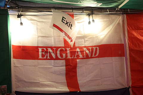 An exit sign hangs above the England flag after the World Cup semifinal soccer match between England and Argentina