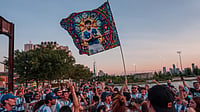 (AP Photo/Adam Gray) : A Diego Maradona flag is held in the air as Argentina fans gather by the Hudson River ahead of their World Cup semifinal soccer match against England, Tuesday, July 14, 2026, in New York.