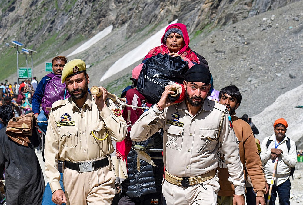 Anantnag Police Mountain Rescue Team (MRT) officials assist a pilgrim during the annual Amarnath Yatra, on the Pahalgam route, in Anantnag district, Jammu and Kashmir. - | Photo: PTI 
