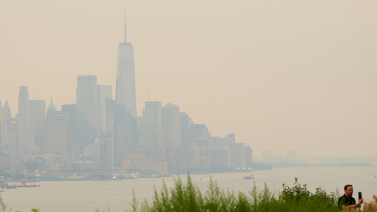 The New York City skyline, shrouded in smoke, is used as a backdrop for a man recording himself in Weehawken, N.J., Thursday, July 16, 2026 - (AP Photo/Seth Wenig)