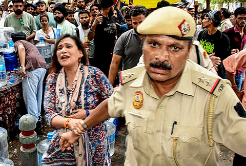 The woman with a police official after she threw an ink-like liquid on Cockroach Janata Party (CJP) founder Abhijeet Dipke as he begins an indefinite hunger strike at Jantar Mantar, in New Delhi.
