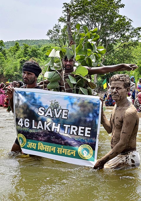 People hold a banner as they stage a 'Jal Satyagrah' against the Ken-Betwa Link Project and other irrigation schemes alleging inadequate rehabilitation and displacement-related grievances, in Chhatarpur district, Madhya Pradesh, Saturday, July 18, 2026. 