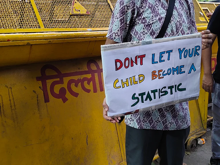 A demonstrator holds a placard during a protest at Jantar Mantar on July 18 demanding the resignation of Union Education Minister Dharmendra Pradhan. | - Ainnie Arif