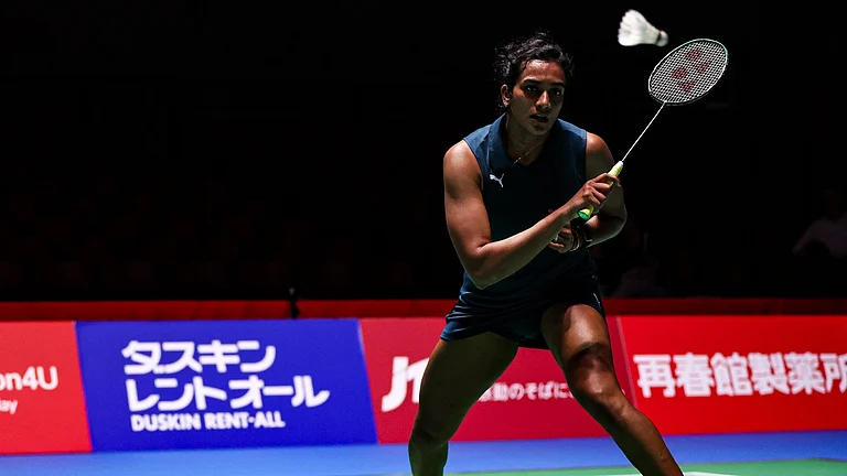 PV Sindhu is captured in an athletic ready stance during her women's singles semifinal at the Japan Open 2026. Wearing a dark blue sleeveless kit with white badminton shoes, the Indian star keeps her eyes firmly on the shuttlecock as she prepares for a backhand return. - PTI