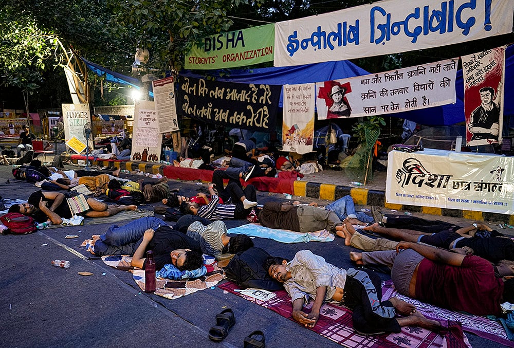 Supporters of the Cockroach Janata Party (CJP) rest at Jantar Mantar before activist Sonam Wangchuk, unseen, who has been on an indefinite hunger strike for 21 days, is shifted to a hospital for medical care, in New Delhi, early Saturday, July 18, 2026. 
