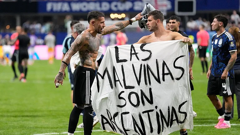 Argentina's Giovani Lo Celso holds a banner with the words "The Malvinas are Argentine", referring to the Falkland Islands, while teammate Argentina's Nicolas Otamendi gestures to him, at the end of the World Cup semifinal soccer match between England and Argentina in Atlanta - Rebecca Blackwell/AP Photo
