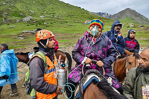 Mountain Rescue Team (MRT) officials assist a pilgrim during the annual Amarnath Yatra, near Sheshnag, Panjtarni, in Anantnag.