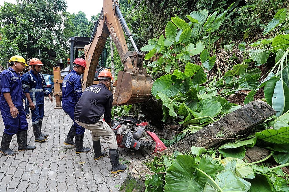 Rescue personnel remove a two-wheeler buried under debris following a landslide, at Kharguli, in Guwahati, Assam.