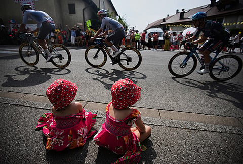 Little girls watch the pack during the fifteenth stage of the Tour de France cycling race, from Champagnole to Plateau de Solaison, France, Sunday, July 19, 2026. 