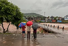 People watch the swollen Mendhar river flowing above the danger level following heavy rains, in Mendhar, Poonch district, Jammu and Kashmir, Monday, July 20, 2026. - | Photo: PTI