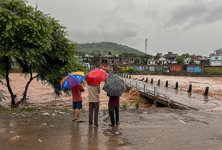 People watch the swollen Mendhar river flowing above the danger level following heavy rains, in Mendhar, Poonch district, Jammu and Kashmir, Monday, July 20, 2026. - | Photo: PTI