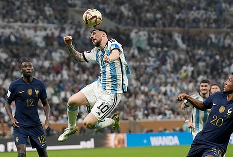 Argentina's Lionel Messi heads the ball next to France's Kingsley Coman, right, during the World Cup final in Lusail, Qatar, Dec. 18, 2022. 