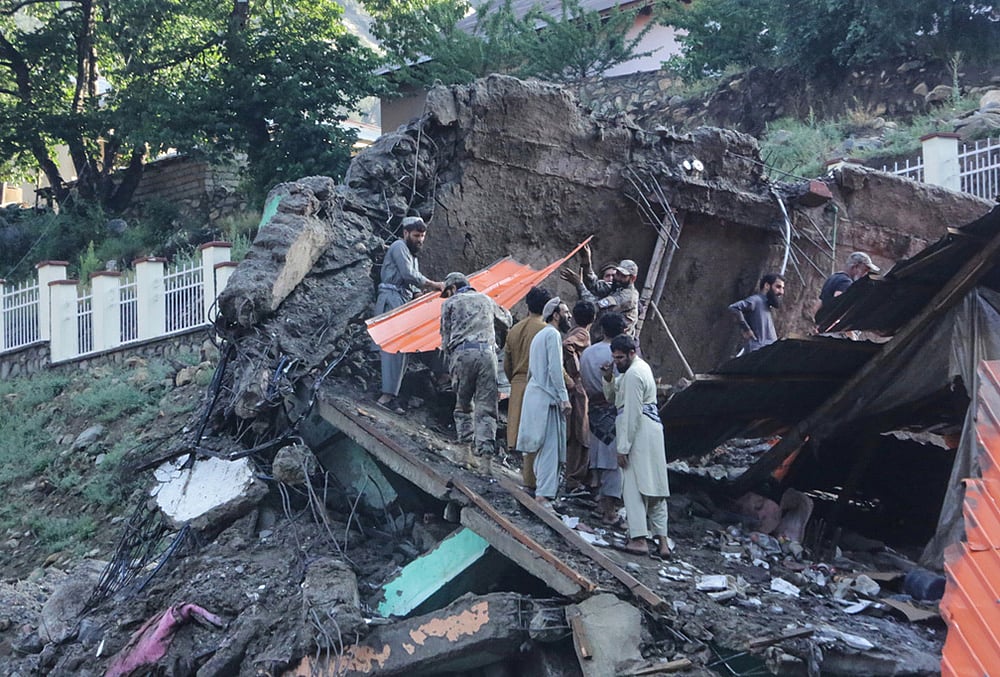 Residents and rescue workers inspect buildings damaged by heavy flooding in the eastern province of Nuristan, Afghanistan, Tuesday, July 21, 2026. 
