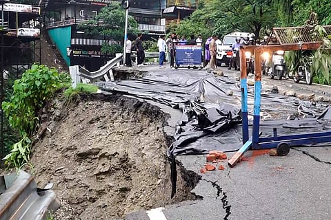 Police cordon off the caved-in section of a road following landslides and heavy rains, on the Dehradun–Mussoorie State Highway.